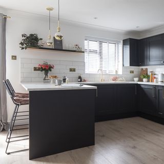kitchen with black units and white tiles with island and bar stool