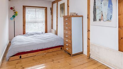 bedroom with white wall and wooden flooring with drawers
