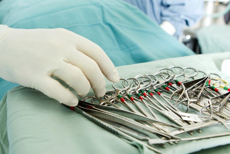 Surgical instruments sit in a tray in an operating room.