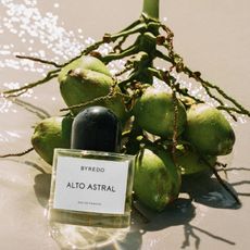 a bottle of perfume next to a pile of coconuts
