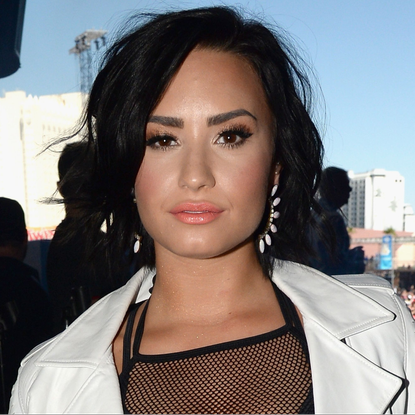 Demi Lovato pouting, wearing make up and white leather jacket