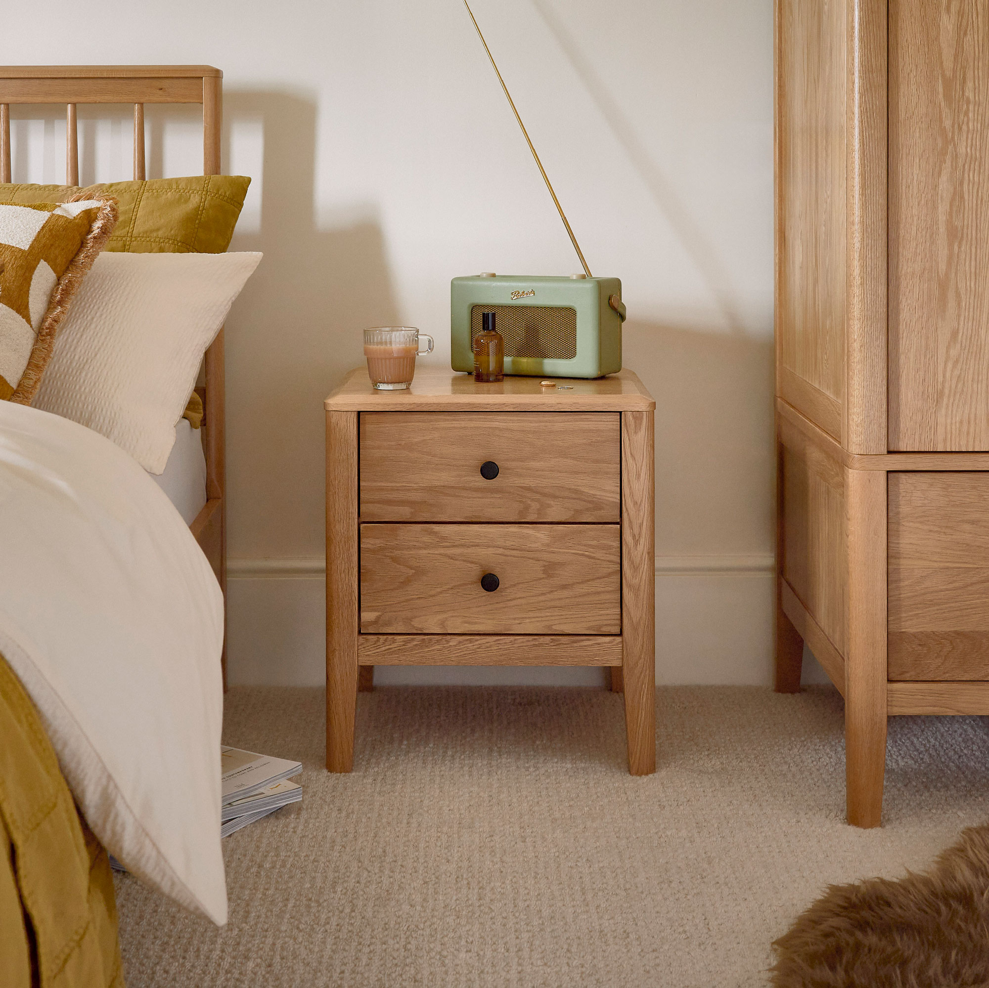 oak two-drawer bedside table with green radio