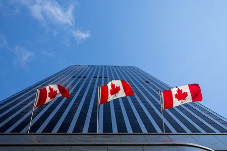 Three flags of Canada in front of a business building in Ottawa