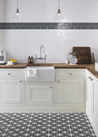 Patterned grey tiles in a small shaker style kitchen with Belfast sink and wood countertops