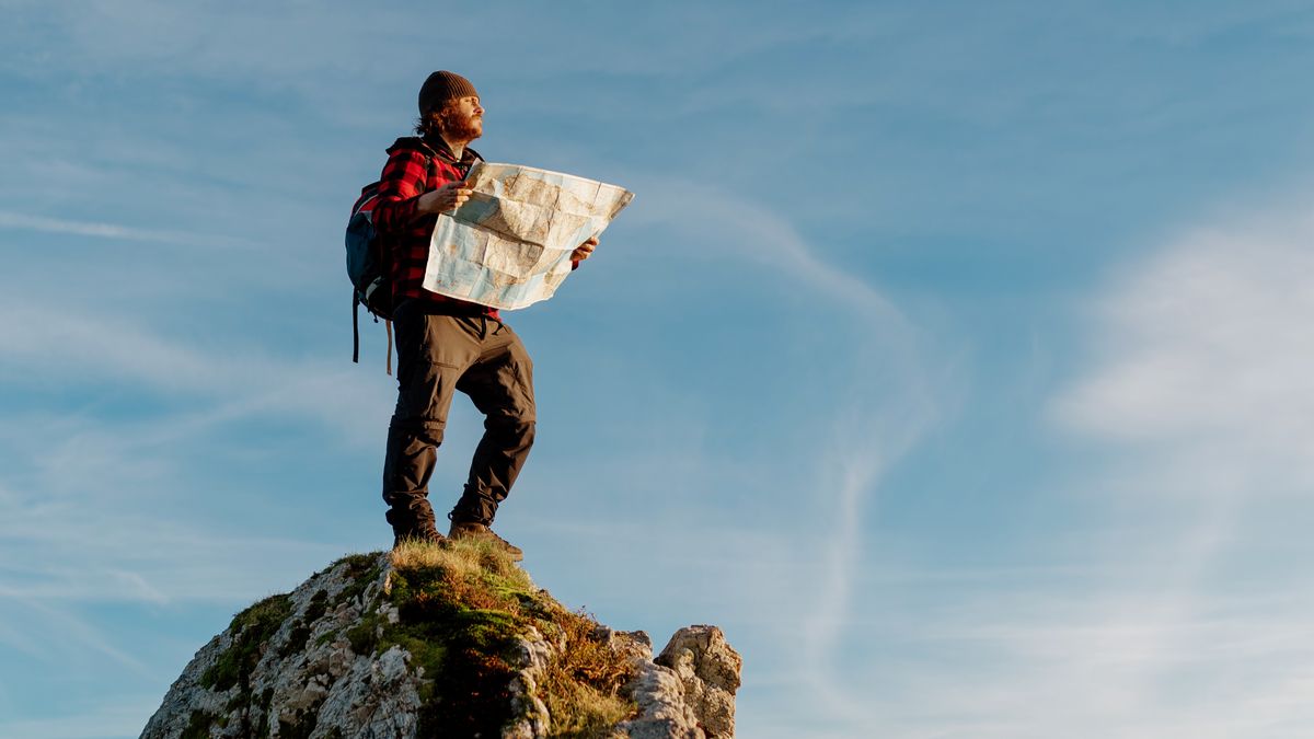 Hiker with map standing on rocky outcrop