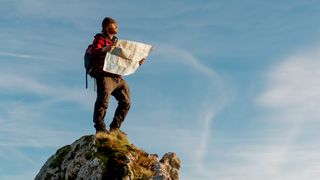 Hiker with map standing on rocky outcrop