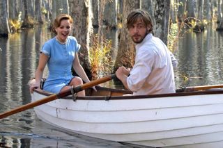 rachel mcadams wears a blue dress while ryan gosling wears a white shirt and they ride a row boat together through a swamp in the notebook