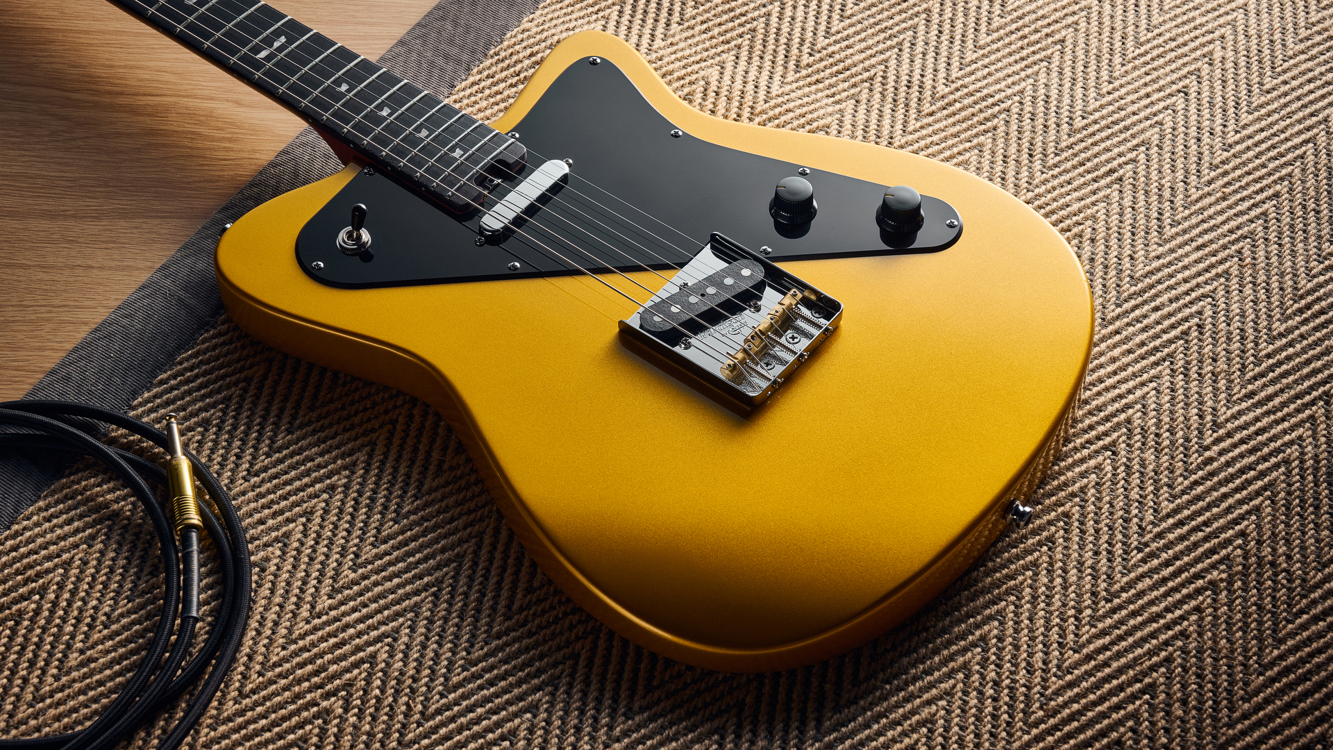 A Baum Guitars Verve lying on a rug with a guitar cable coiled nearby