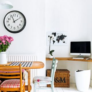 dinning area with white wall wooden dinning table with chairs clock on wall and computer on wooden desk