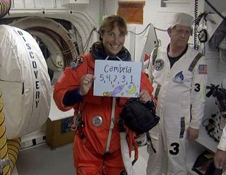 NASA astronaut Dottie Metcalf-Lindenburger displays a signto her daughter before boarding the space shuttle Discovery.