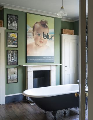 green bathroom with roll top bath and artwork on the walls