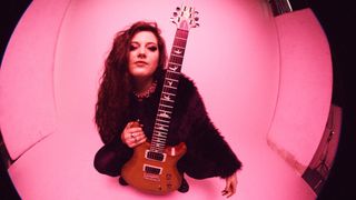 Claire Genoud with a PRS guitar on pink background