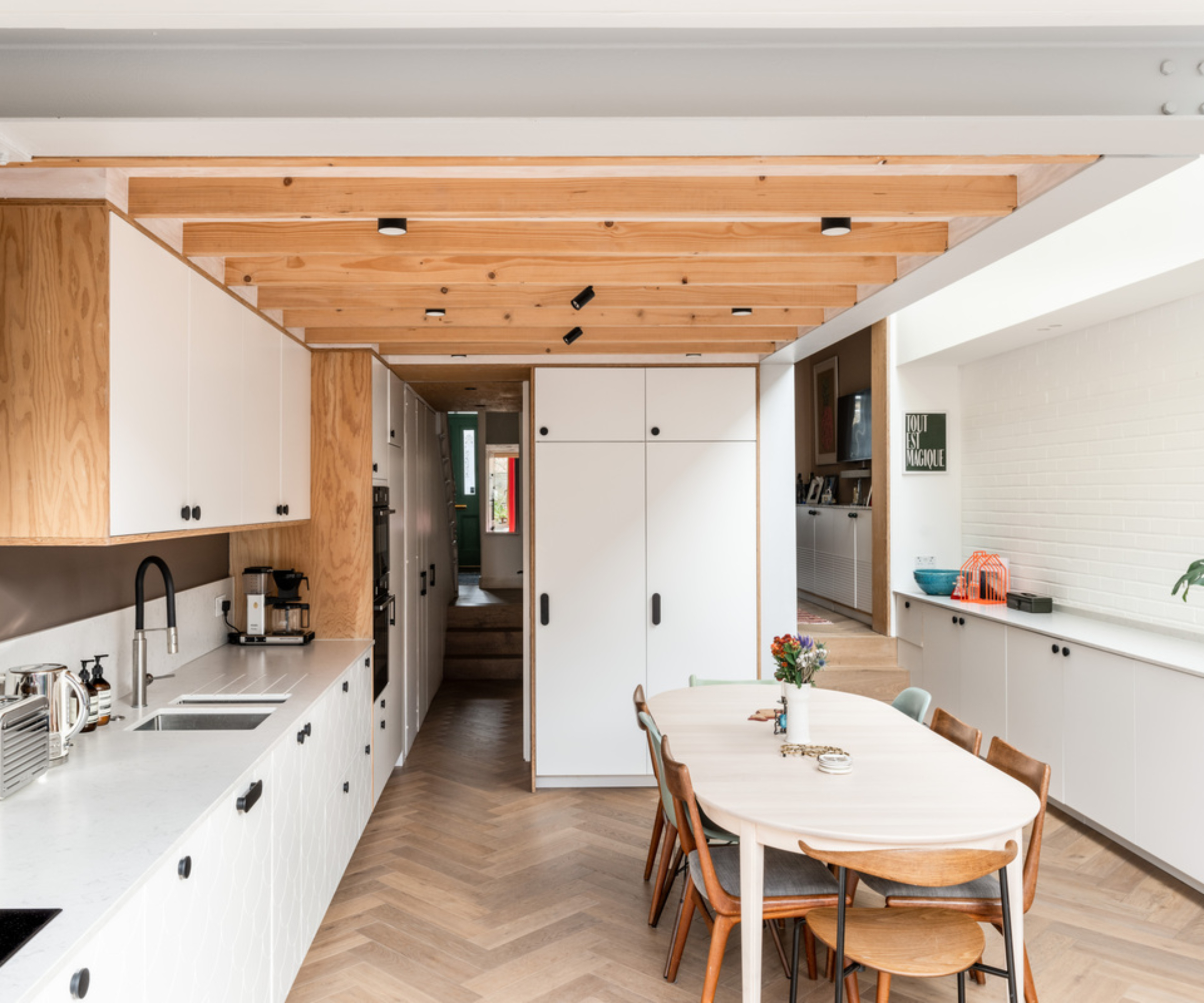 inside kitchen extension with timbers on inside of roof, white units, narrow skylight along one section of roof