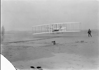  Flyer 1, controlled by Orville Wright, makes history’s first powered flight at Kitty Hawk, North Carolina, on Dec. 17, 1903. Orville’s brother Wilbur looks on in this photo, which was taken by John Daniels, a member of the U.S. Life-Saving Station in Kill Devil Hills, North Carolina.