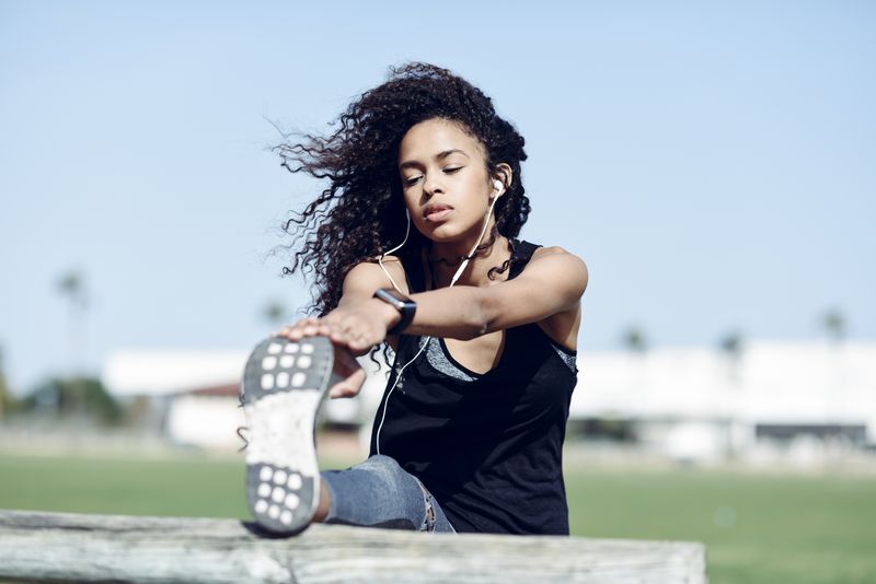 A woman stretching her leg on a bench outdoors