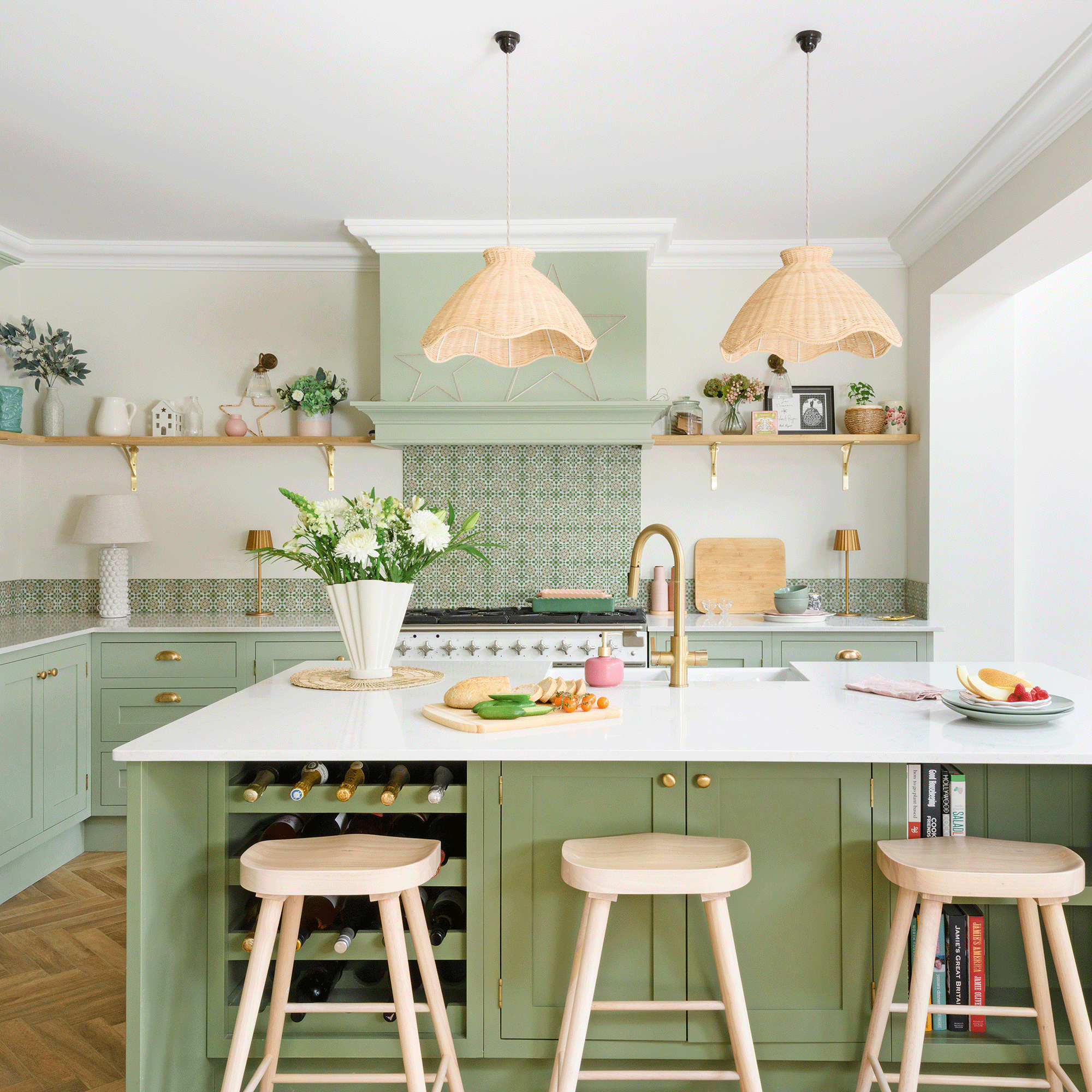 Green kitchen cabinets with white countertop and wooden stools