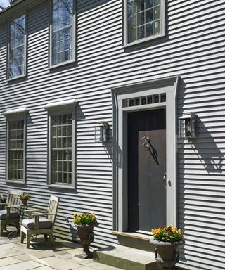 exterior of house with grey wall chair and potted plants