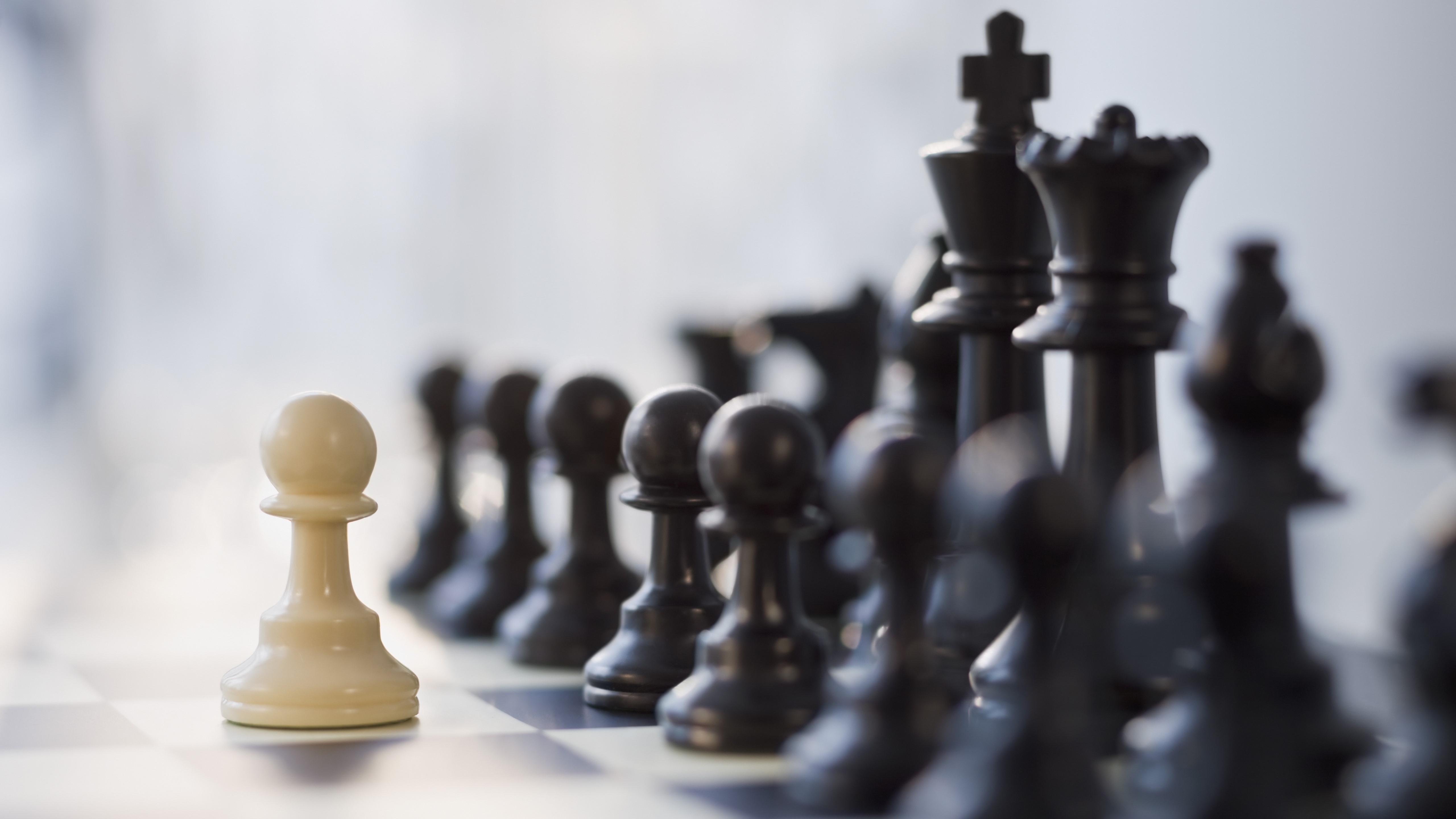 A lone white pawn faces down the black pieces in chess.