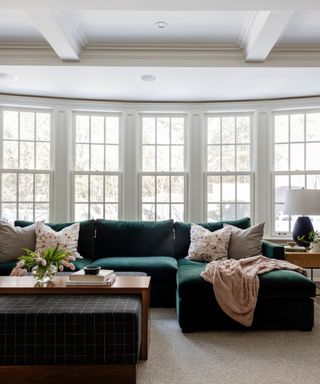 Light living room with large windows, white walls and green velvet couch