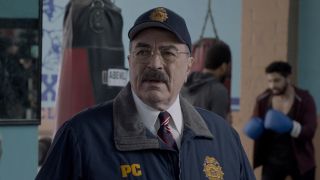 Tom Selleck's Frank Reagan in PC uniform in front of a punching bag in a gym on Blue Bloods