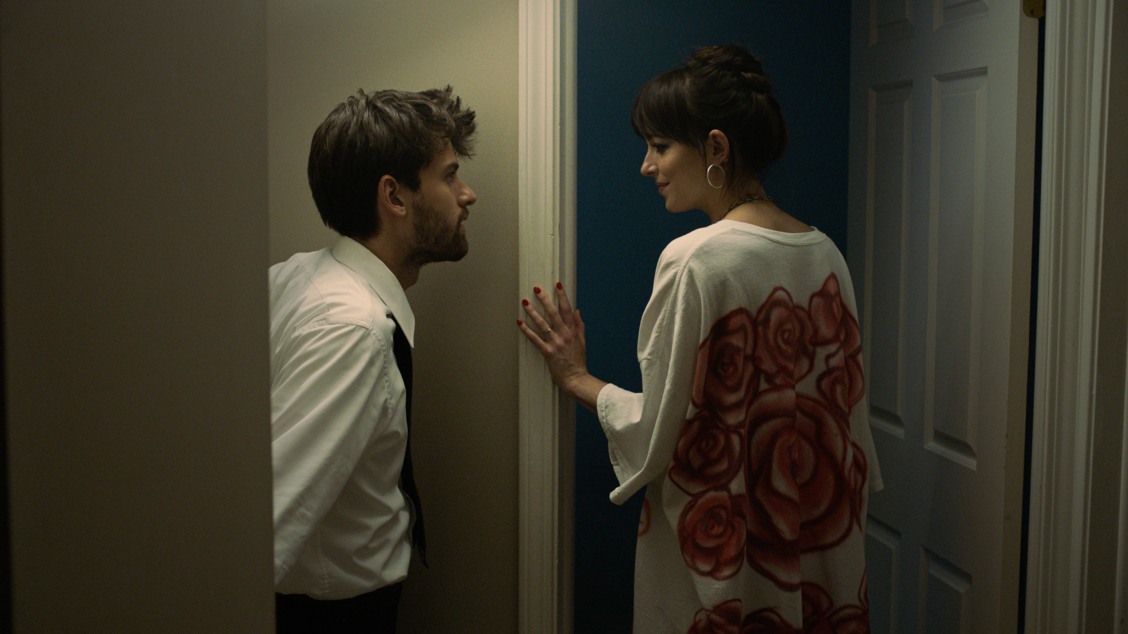 (De izquierda a derecha) Cooper Raiff como Andrew, compartiendo una mirada con Dakota Johnson como Domino, en Cha Cha Real Smooth, cuando está a punto de entrar en una habitación.