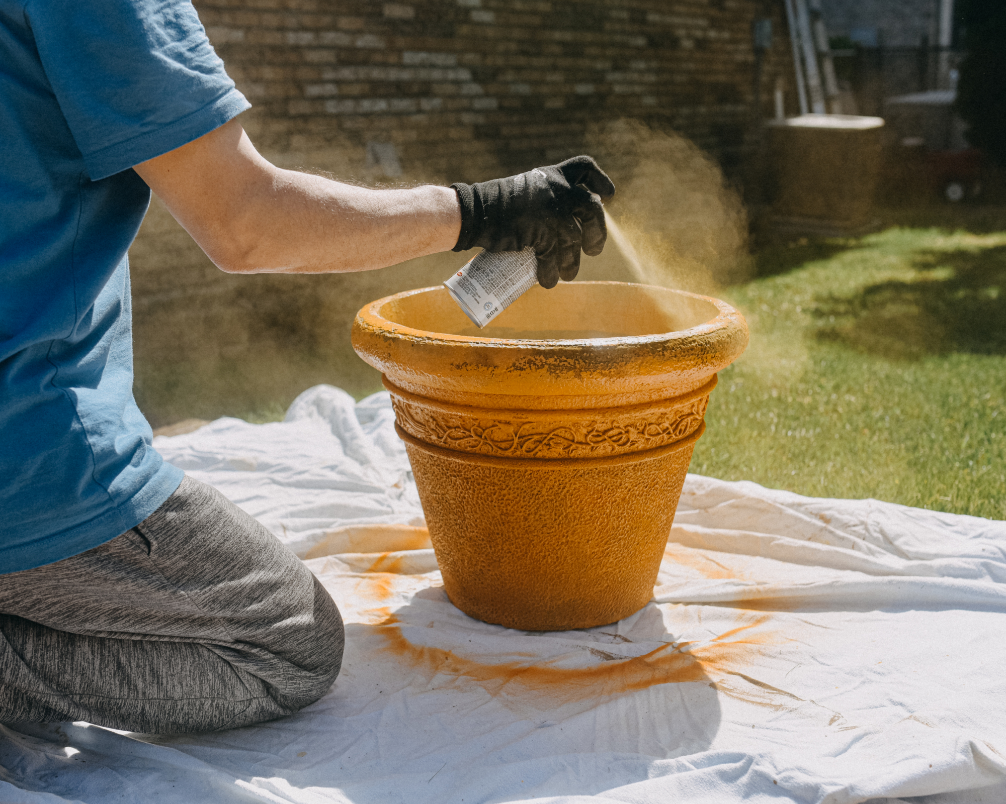 man using spray paint to change the color of a large planter