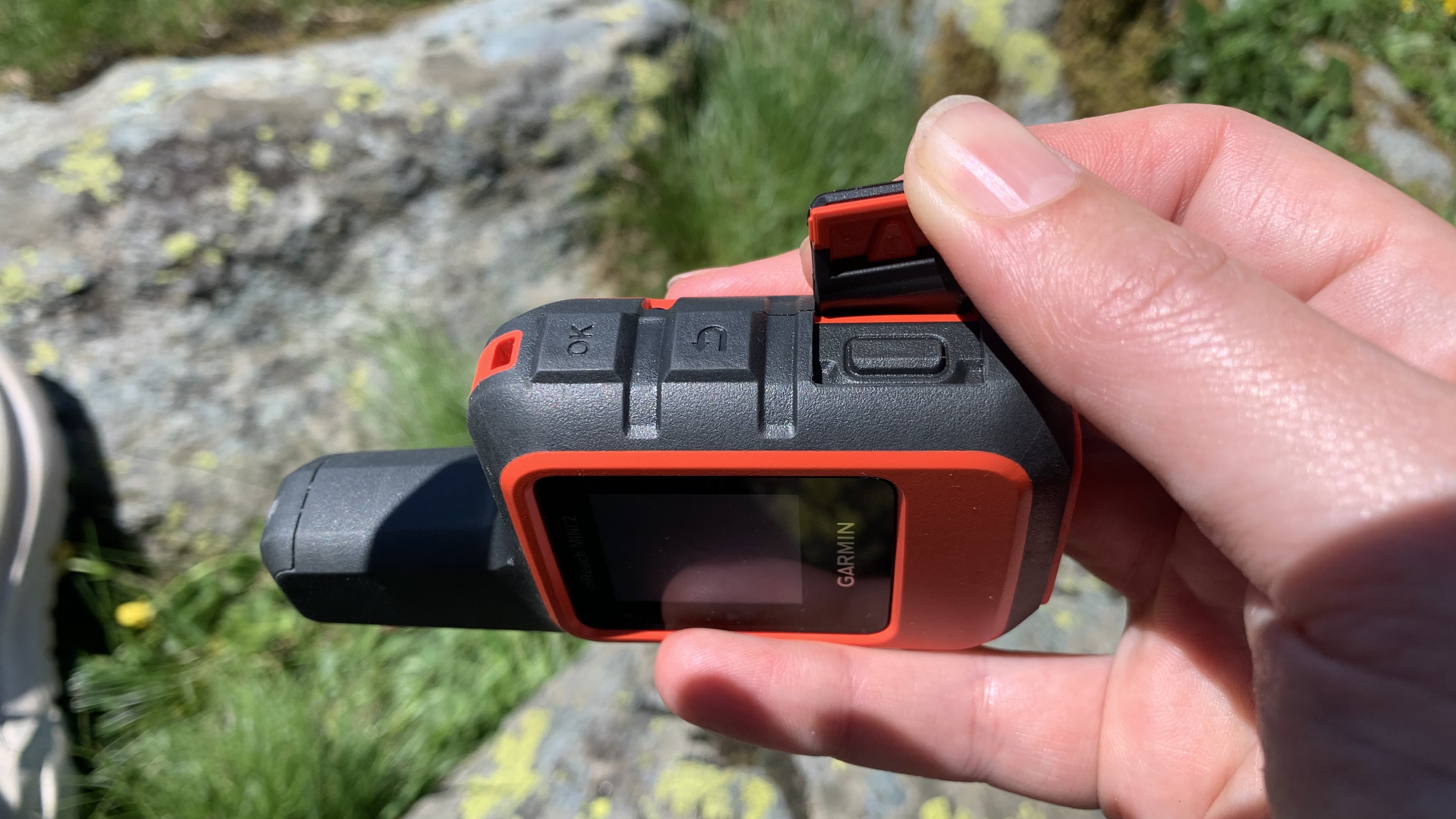 Hand shows the SOS button on the Garmin inReach Mini 2
