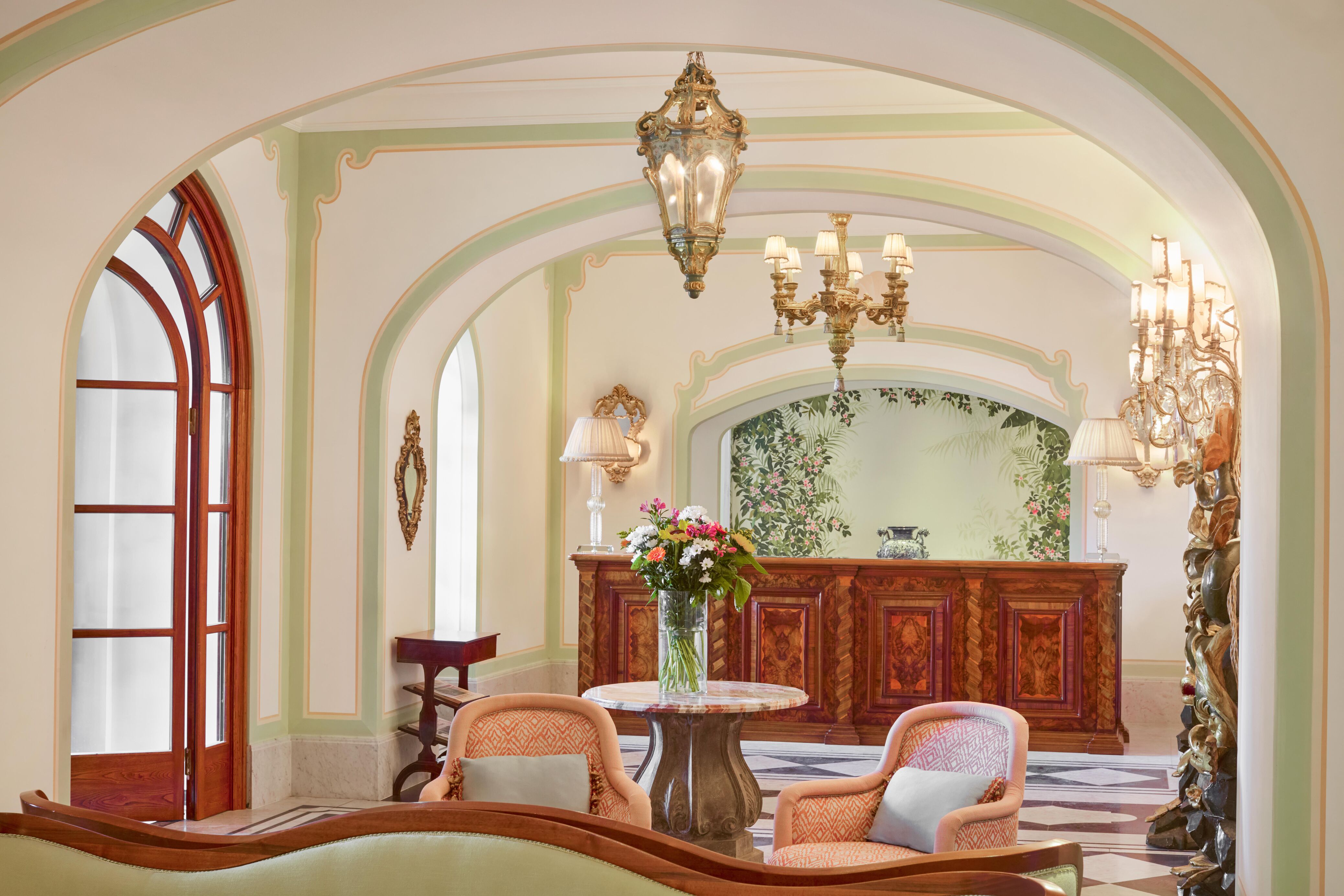 The lobby of Hotel Splendido; whitewashed walls with pale green accents and coral-coloured armchairs