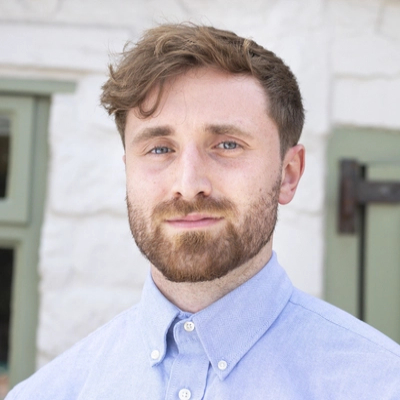 male with short hair and beard wearing pale blue collared shirt