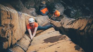 rock climber looking up at the camera while climbing a dramatic basalt column near Vernon, BC