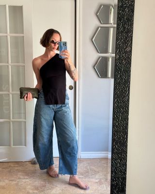 a woman takes a selfie in barrel jeans and jelly sandals
