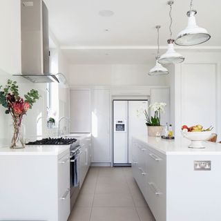 A white kitchen with industrial lighting above an island