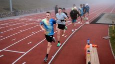 Group of runners training on a running track in misty weather