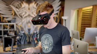 Beste VR-spill: En person som benytter et svart VR-headsett med røde detaljer i et kontormiljø.