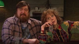 Kate McKinnon and John Goodman in character as drunks sitting at a bar before last call.