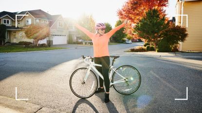 Smiling woman with arms outstretched on road bike ride on fall afternoon, representing the benefits of cycling