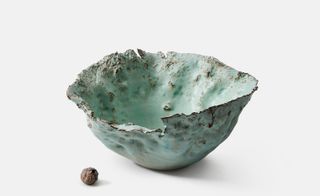 An old mint-blue coloured bowl with rough edges and a loss of colour in some parts.