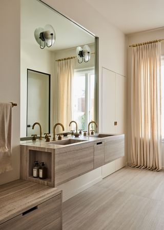 A bathroom with travertine flooring and brass faucets