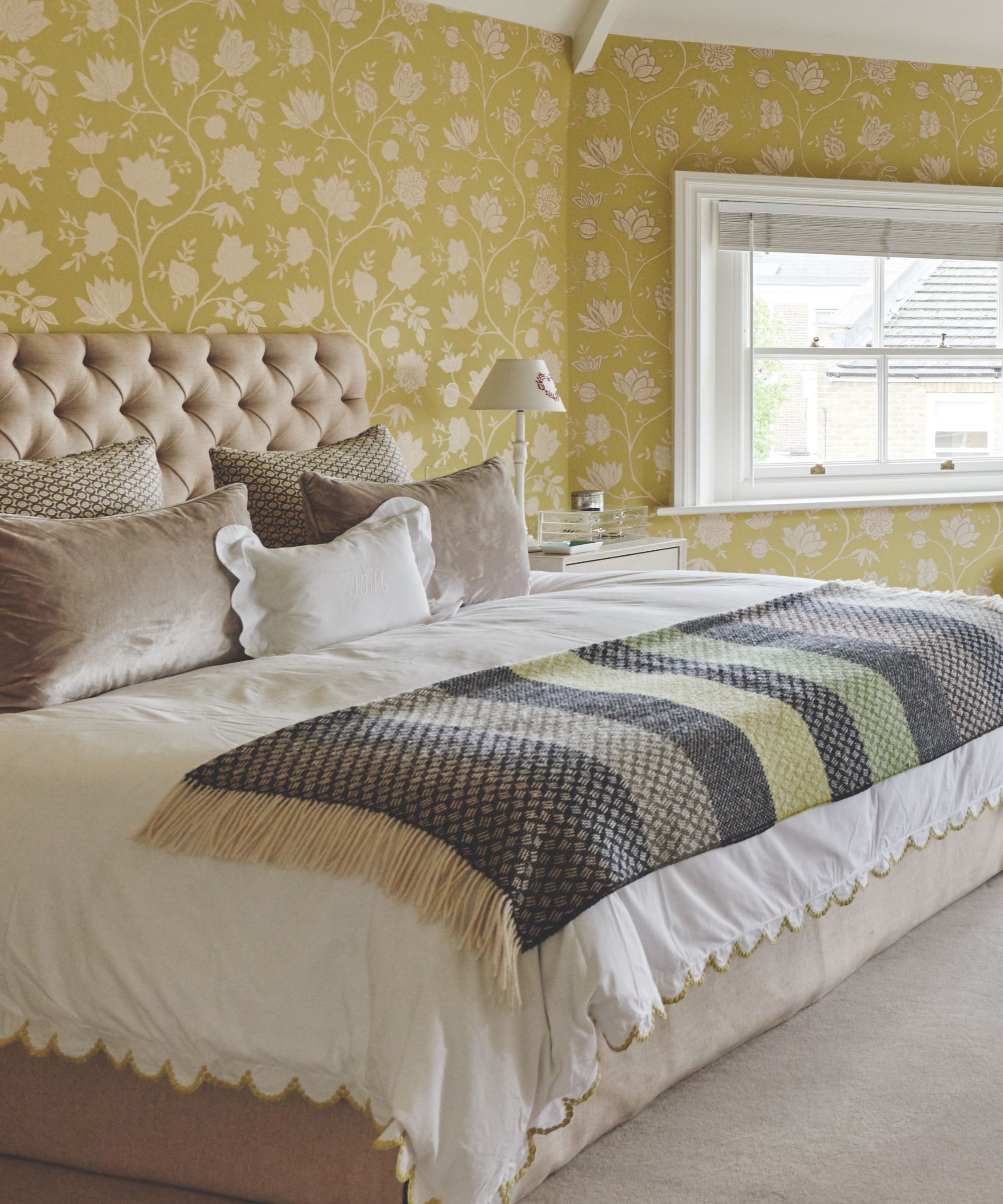 Bedroom with yellow floral wallpaper, white bedding, and a gray and yellow patterned throw