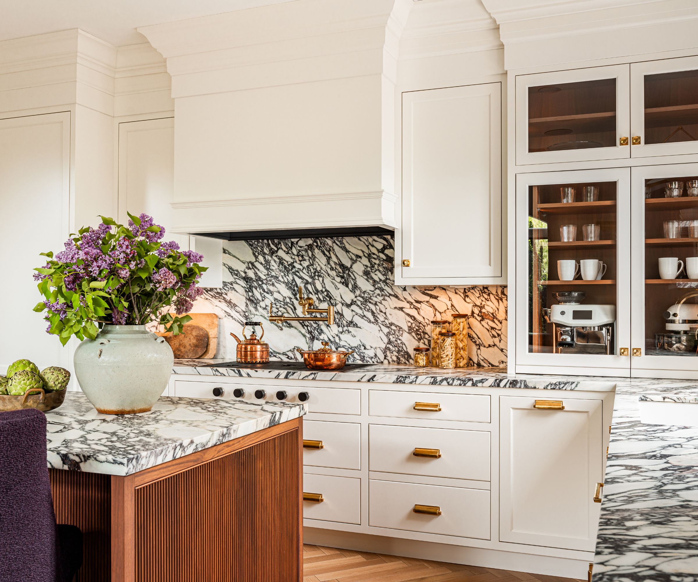modern kitchen with warm white cabinets and marble counters and backsplash