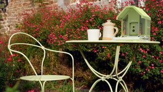 Birdfy Feeder Metal sitting on an outdoor dining table in a garden