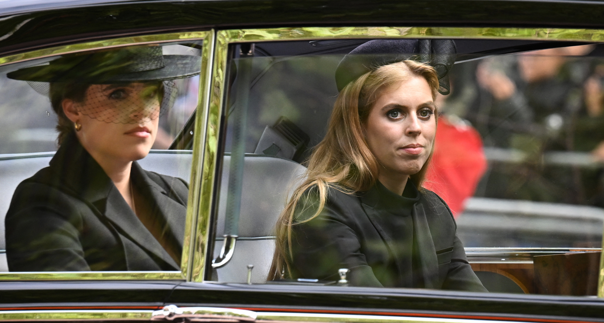 Princess Beatrice and Princess Eugenie wearing black riding in a car