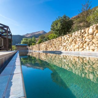 swimming pool with stone wall and mountain view
