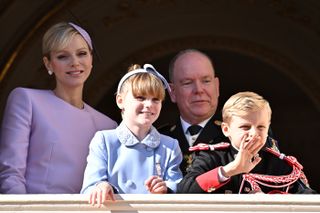 Princess Charlene, Prince Albert, Prince Jacques and Princess Gabriella waving on a balcony on National Day 2024