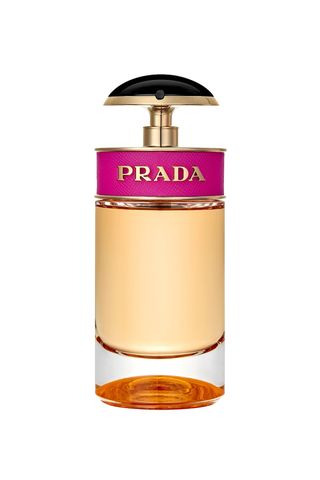 Prada Candy Eau De Parfum Spray in circular golden bottle with hot pink Prada band and circular black pump on white background 