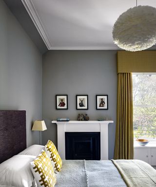 An example of how to plan bedroom lighting showing a white feather pendant ceiling light above a bed with decorative gold cushions