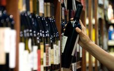 A bottle of wine being removed from a shelf of wines