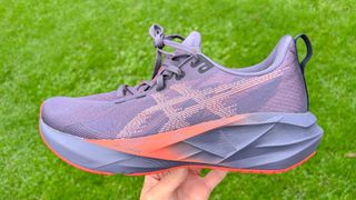 Asics Novablast 5 held in a person's hand outside