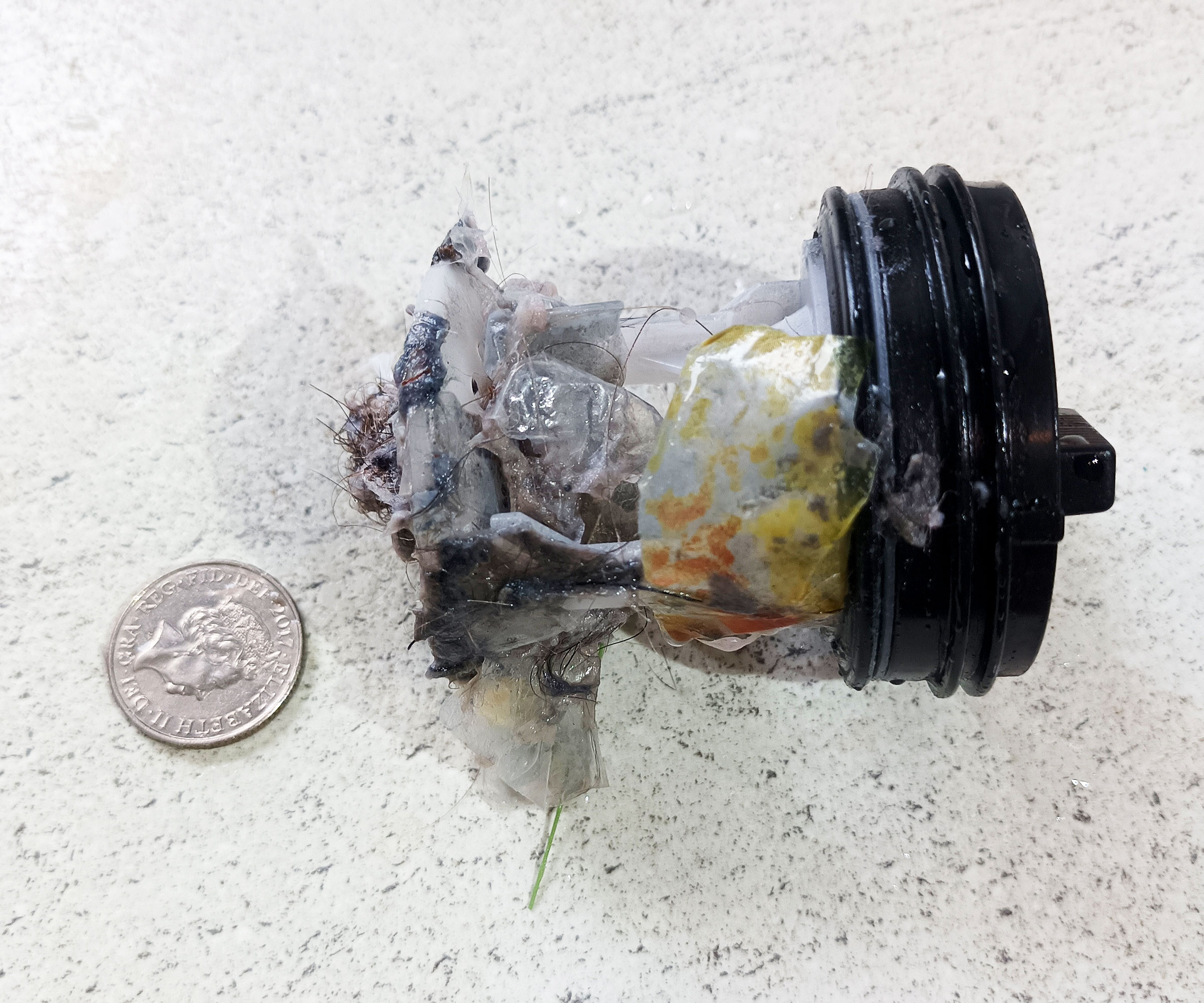 Blocked washing machine filter with coin to one side on kitchen worktop