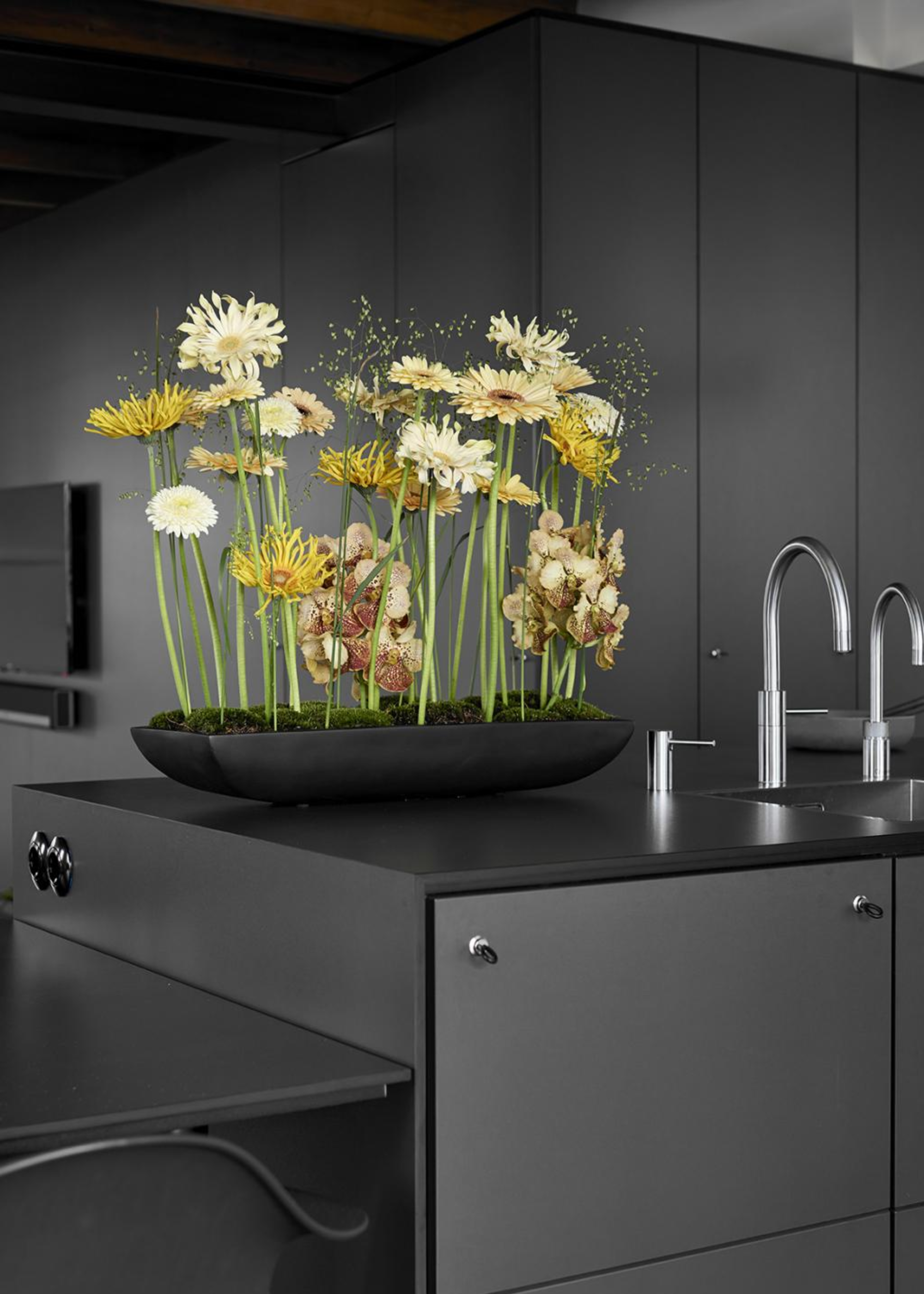 A long moss flower arrangement with yellow and white flowers